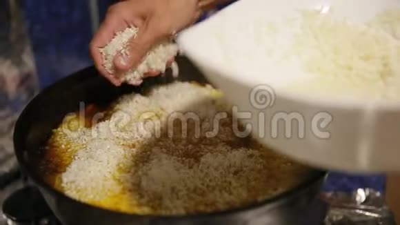 煮饭时沙夫把白米加入铸铁水壶用勺子把它移开视频的预览图