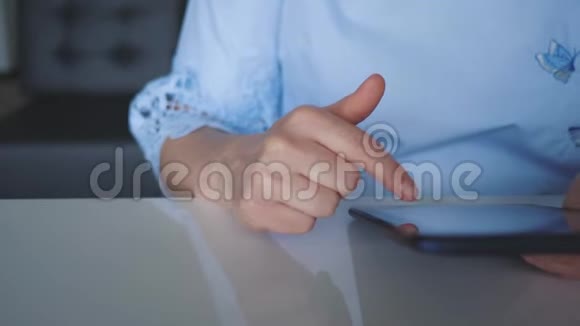 一个年轻的女孩坐在一张桌子旁手里拿着一杯咖啡一块数字平板电脑翻阅着目录视频的预览图