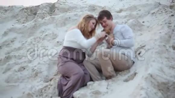 男孩和女孩和一只狗坐在沙滩上视频的预览图