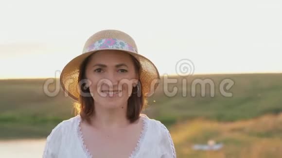 日落时戴帽子的女人的肖像视频的预览图