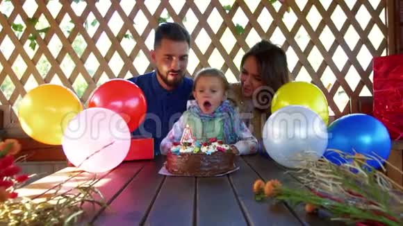 阳光明媚的小女孩在她的蛋糕上吹蜡烛而他们正在庆祝女孩的生日视频的预览图