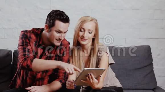 男人和女人在沙发上拿着一块平板电脑视频的预览图