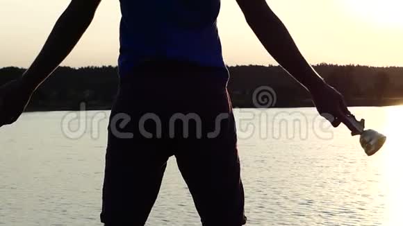 阳光明媚的人在夕阳西下的湖面上举起一个胜利者的碗视频的预览图