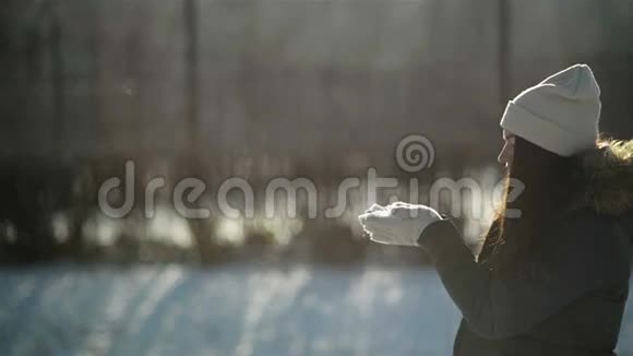 玩耍的女孩喜欢外面寒冷的阳光天气人物中令人惊叹的女人正从她的手中吹着雪花视频的预览图