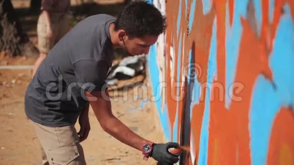 涂鸦艺术家在街墙上画画帅气的男人用喷雾瓶喷着五颜六色的油漆城市视频的预览图