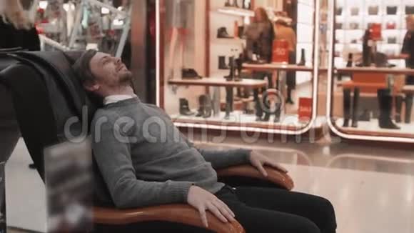 商场里的男人躺在按摩椅上近距离拍摄视频的预览图