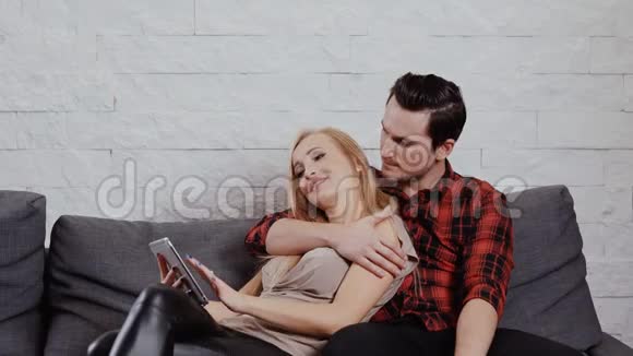 男人和女人在沙发上拿着一块平板电脑视频的预览图