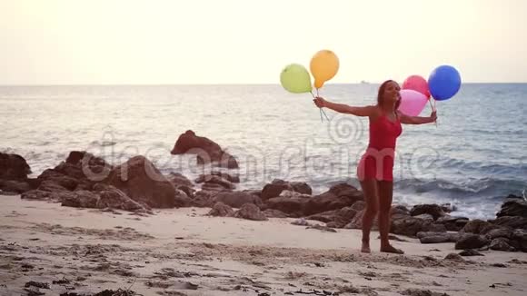 快乐的年轻美丽的女人手里拿着气球在海滩上缓慢地奔跑关于生日和快乐的概念视频的预览图