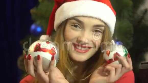 戴着圣诞帽的可爱少女手里拿着圣诞玩具看着相机微笑着视频的预览图