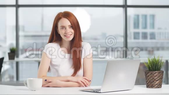 商务女性坐在桌子旁手提电脑看着相机视频的预览图