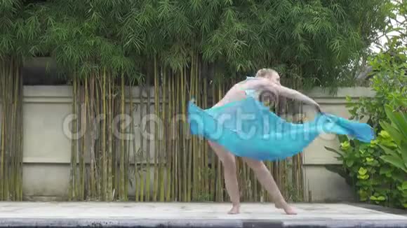 年轻苗条的女子在热带度假胜地的泳池边跳东方舞视频的预览图