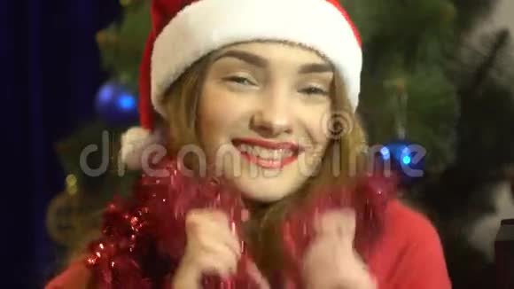 活泼开朗的年轻女孩脖子上戴着一顶戴着圣诞帽的Tinsel跳舞视频的预览图