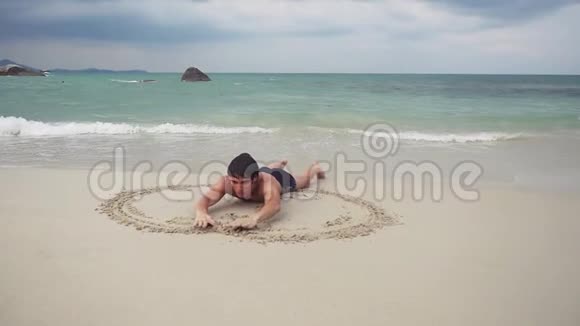 年轻人在海滨潮湿的沙滩上画了一个心脏符号慢动作1920x1080视频的预览图