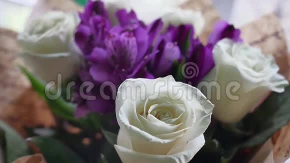 特写镜头上的一束束美丽的白花玫瑰正站在一个节日礼物的女人室内视频的预览图