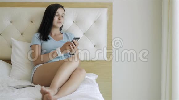 清晨躺在床上使用智能手机的少女视频的预览图