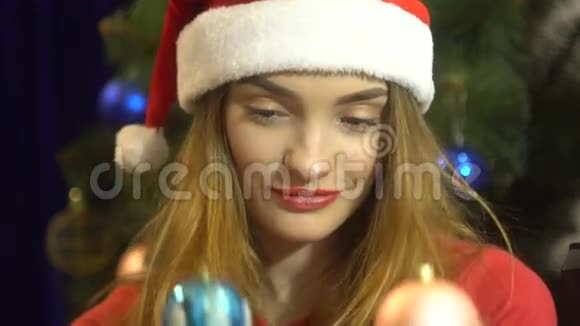 戴圣诞帽的迷人少女选择圣诞玩具装饰一棵树视频的预览图