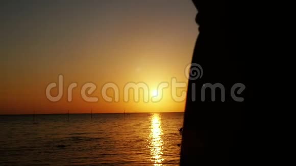 快乐的女人穿着裙子在海滩上奔跑慢悠悠地旋转着举起双臂享受日落时的自由视频的预览图