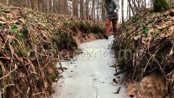 人在森林里冰冻的小溪上奔跑和滑行前景视频的预览图