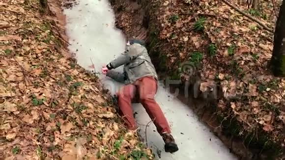 当一个人在森林里的冰面上滑倒时镜头拍摄下来视频的预览图