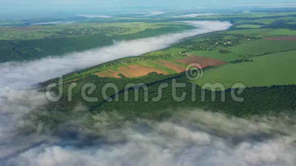 在云层上方的山上鸟瞰田野日出时鸟瞰河流上空的雾浓雾笼罩河流视频的预览图