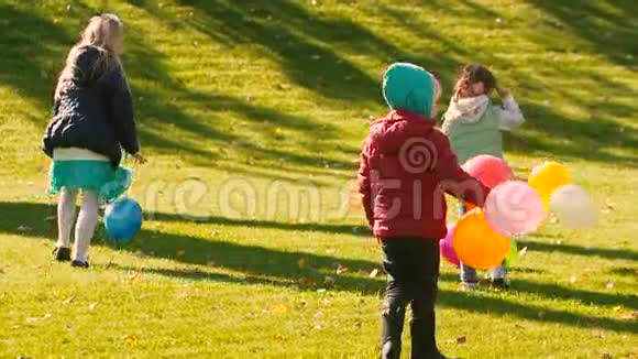 三个小女孩从绿色和黄色的草地上捡起气球视频的预览图