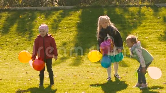 三个快乐的小女孩把他们五颜六色的气球扔到空中视频的预览图