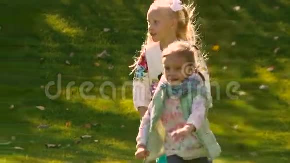 两个快乐的小女孩在绿色的草地上积极地奔跑特写镜头视频的预览图