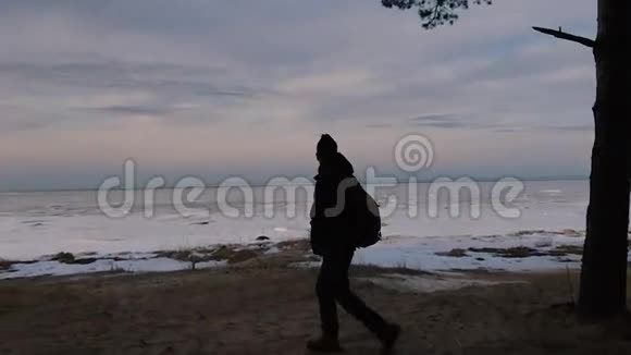带着背包的人正在天空和海湾的背景下沿着海岸行走视频的预览图