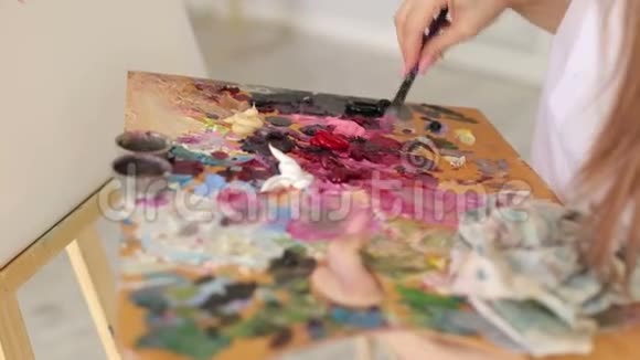 艺术家用画笔在调色板上混合油画视频的预览图