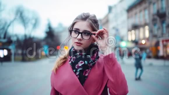 女人朝相机走去环顾四周摸着她的眼镜时髦的样子城市环境视频的预览图