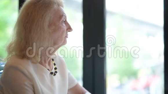 老年妇女透过窗户看视频的预览图