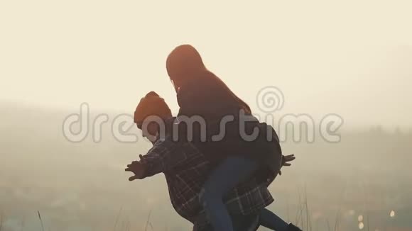 年轻的一对相爱的夫妇在享受高山的假期有魅力的男人把女朋友扛在肩上旋转着视频的预览图