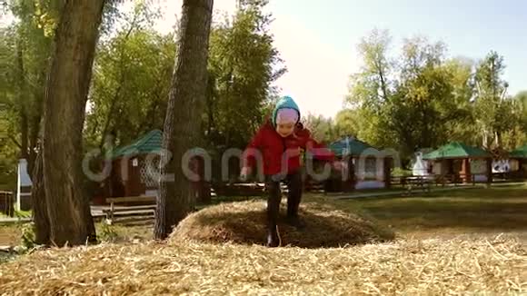 可爱的微笑的小女孩从一个干草堆跳到另一个干草堆视频的预览图