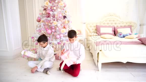 新年过后的早晨快乐男孩的孩子们在舒适的卧室里打开了圣诞礼物视频的预览图