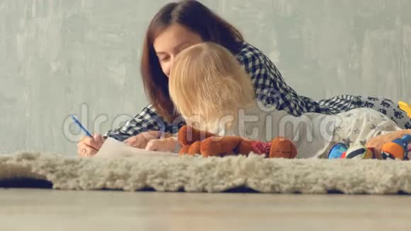 母女女孩用铅笔画一幅画妈妈拥抱和亲吻宝贝视频的预览图