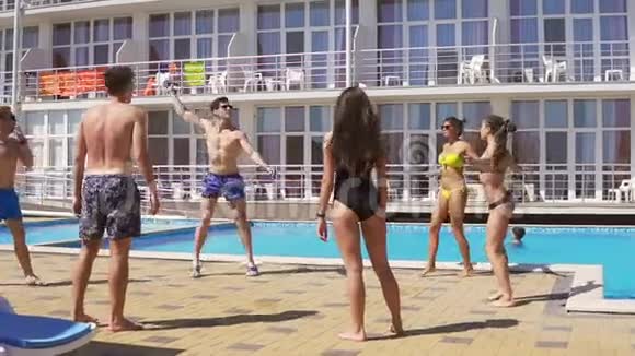 一群年轻的朋友在游泳池边打排球夏日泳池派对慢镜头视频的预览图