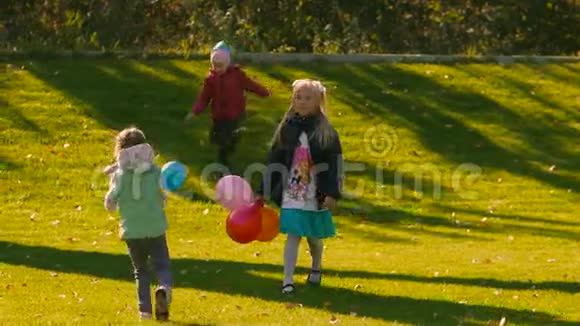 有趣的小女孩在绿色草地上玩五颜六色的气球视频的预览图