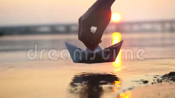 在美丽夕阳西下的海面上人们手里拿着纸船把它推开视频的预览图