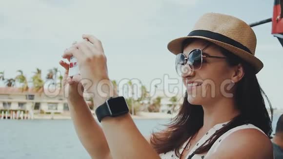 美丽的微笑女孩戴着眼镜戴着帽子在热带自然阳光明媚的艾尔斯海滩的背景下打电话拍照视频的预览图