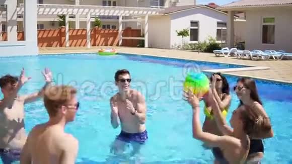 一群年轻朋友在游泳池里玩排球夏日泳池派对慢镜头视频的预览图