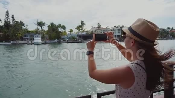 迈阿密阳光明媚的艾尔斯海滩星岛豪华大厦的年轻女孩在船上用电话拍照视频的预览图
