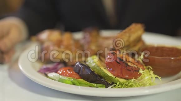 在高级餐厅用刀叉把人手上的视野拉近切出美味的烧烤蔬菜炒鸡肉餐视频的预览图