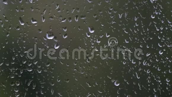阴沉的雨天模糊的植物群背景特写的秋日窗玻璃上的雨滴视频的预览图
