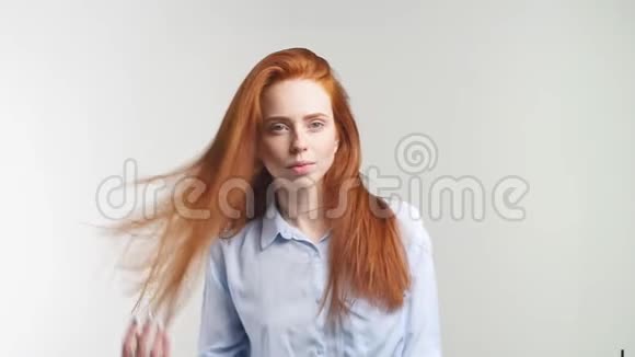 漂亮开朗的红发女孩一头卷发笑着看着白色背景上的相机慢慢视频的预览图