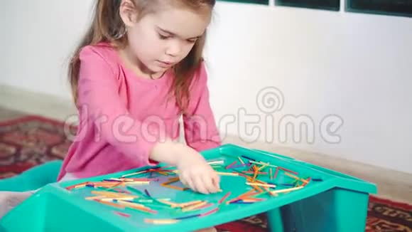女孩在地板上玩五颜六色的木棍视频的预览图
