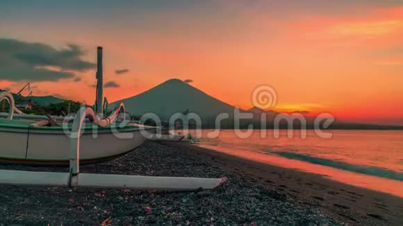 日落时俯瞰阿贡火山背景是一艘渔船在阿米德的杰梅鲁克湾海滩上视频的预览图