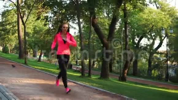 年轻女子在阳光明媚的城市公园跑步户外运动稳定射击慢动作上午视频的预览图