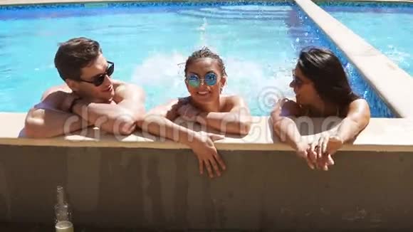 快乐的一群朋友享受夏天的游泳池聚会在水中飞溅和踢腿有吸引力的年轻人视频的预览图