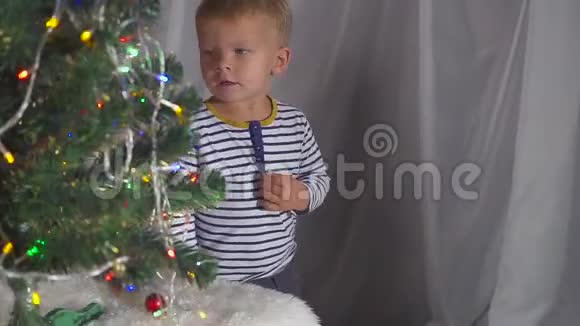 两岁的男孩在圣诞树上玩圣诞玩具关门圣诞树附近一个孩子的肖像视频的预览图