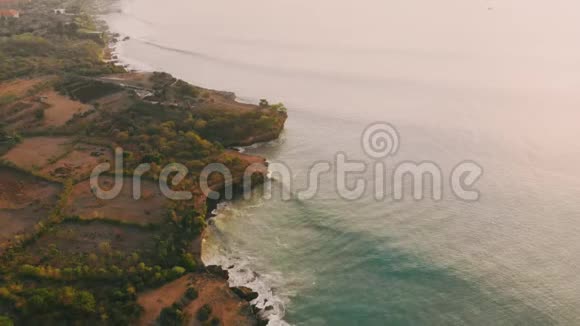 温暖日落时热带岛屿悬崖和海洋的鸟瞰图视频的预览图